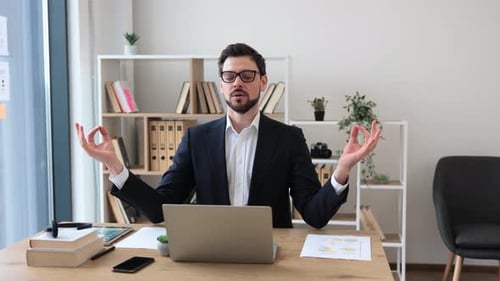 Man Meditating at Computer Desk Practicing Mindfulness in Modern Office Setting