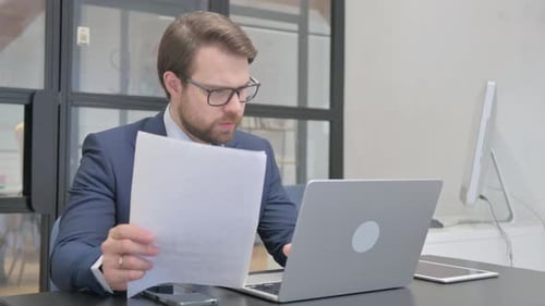 Man with Laptop Reviews Documents and Celebrates