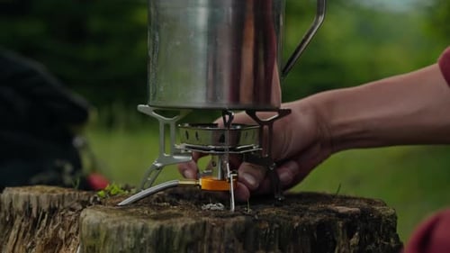 Person Turning on Camping Stove in Forest