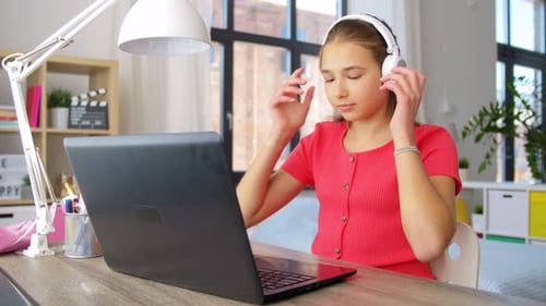 Teen Girl Using Laptop Computer Wearing Headphones