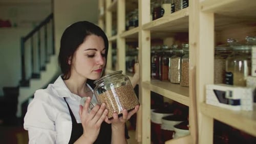 Young woman shop assistant smelling organic products in a zero waste store