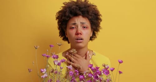 Une femme afro-américaine frustrée souffre d'une crise d'allergie printanière près de fleurs sauvages