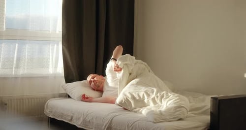 Man Waking Up and Stretching in Bed