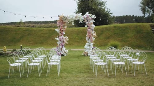 Outdoor Wedding Venue with Floral Arch and White Chairs