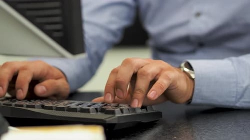 Businessman typing on computer keyboard working in office.