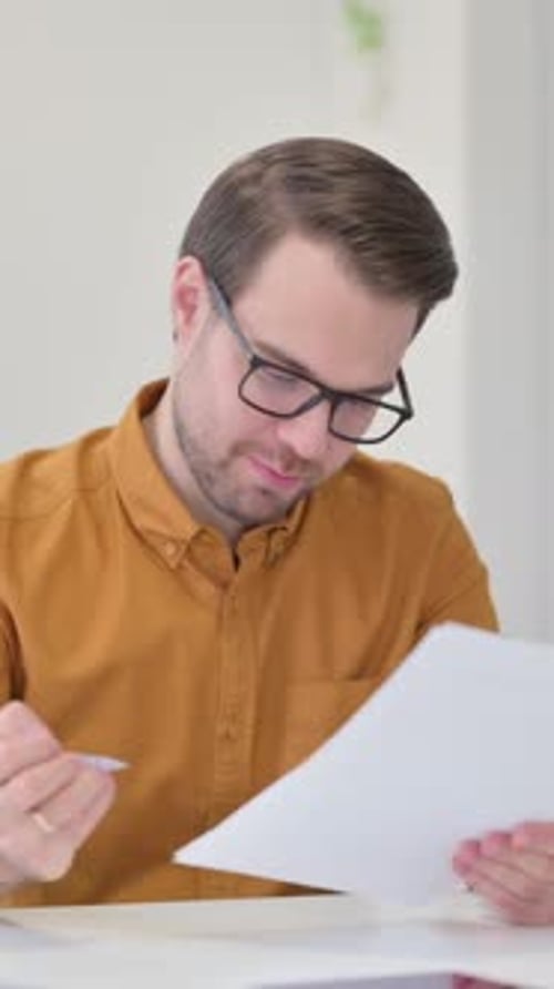 Man Reviews Documents with Positive Reaction Indoors