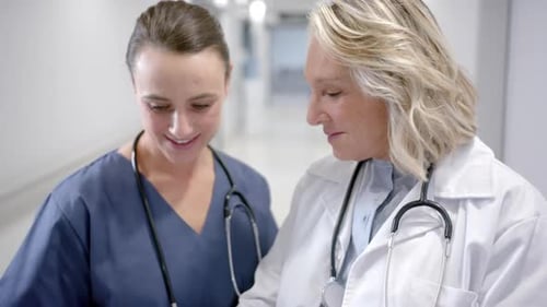 Caucasian female doctors in discussion in hospital corridor, slow motion
