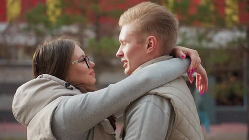 Lovers Embrace Warmly As Wife Kisses Husband Under Autumn Trees Near Colorful Hall