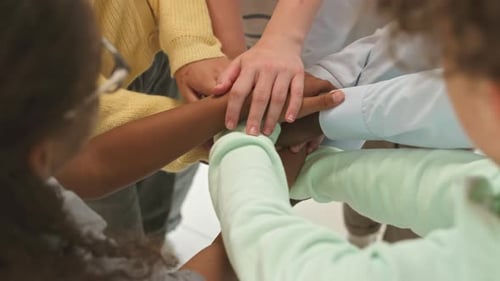 School Children and Teacher Putting Hands Together in Class