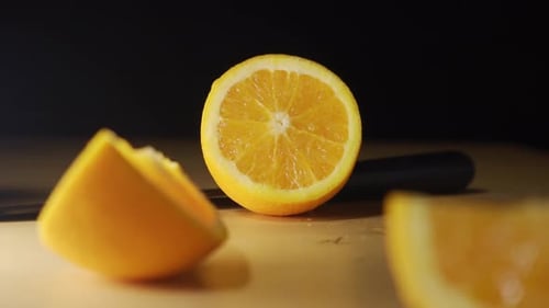 Freshly cut orange fruit with knife laying on the table with black screen background.