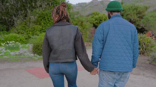 A Man and a Woman are Holding Hands While Walking Down a Path