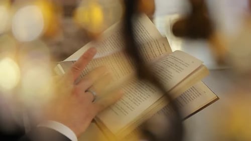 The groom reads a book in a ringed hand close-up