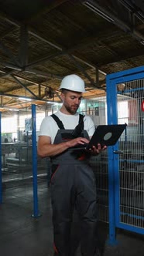 Industrial Worker Programmer Sets Up Production Line Conveyor with Laptop
