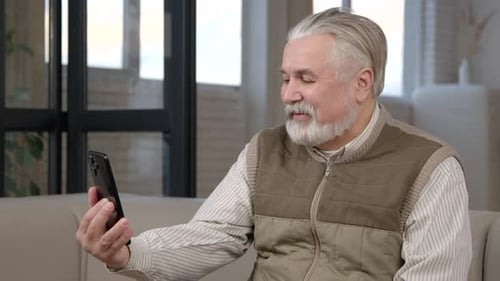 Senior Man Video Calling on Smartphone Indoors