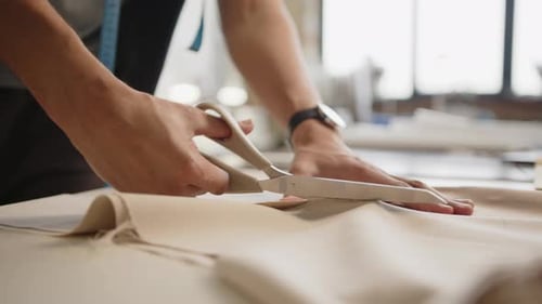 Tailor Using Scissors to Cut Fabric in Dressmaking Workshop