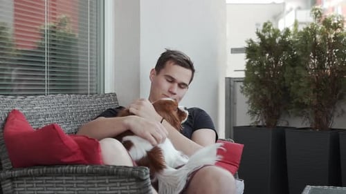 Man Cuddling Cavalier King Charles Spaniel Dog on Balcony