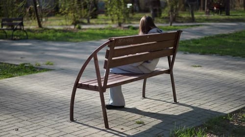 Female Sitting Outdoors Woman Viewed From Behind As She Relaxes Outside in Park Young Lady Sitting