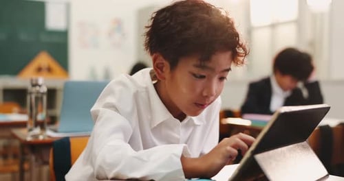 Boy, child and tablet for learning in class, education and online for knowledge in Japan