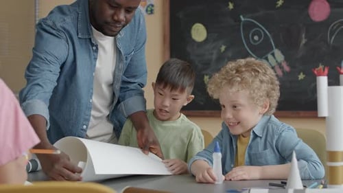 Little Boys Laughing while Making Paper Craft with School Teacher