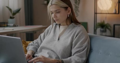 Woman Works on Laptop at Home on Couch