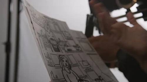 Unrecognizable Producer and Videographer Discussing Storyboard in Studio