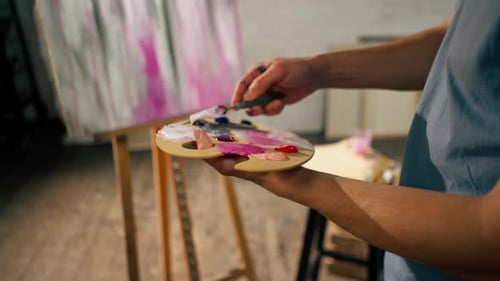 Closeup in an Art Studio an Artist Mixes Color on Palette Holding in His Hands