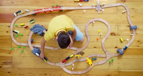 Child Playing with Toy Train on Wooden Floor
