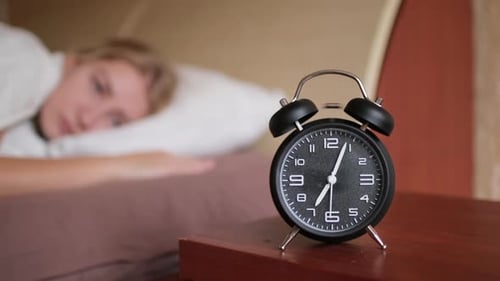 Frau wacht mit klingelndem Wecker um 7 Uhr auf Alltägliche Morgenroutine