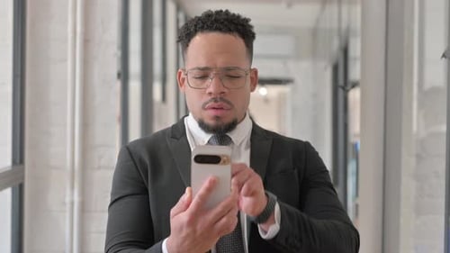 Man in Suit Cheering While Looking at Smartphone