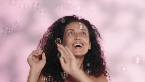 Tender Beautiful Woman with Naked Shoulders in the Studio on a Pink Background with Highlights