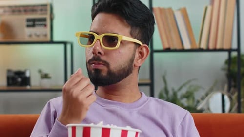 Man Watching TV with 3D Glasses Eating Popcorn