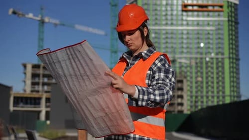 Woman Engineer Looks at Building Plans on Construction Site