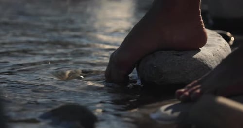 Barefoot man splashes toe carefree in refreshing river water on a summer day