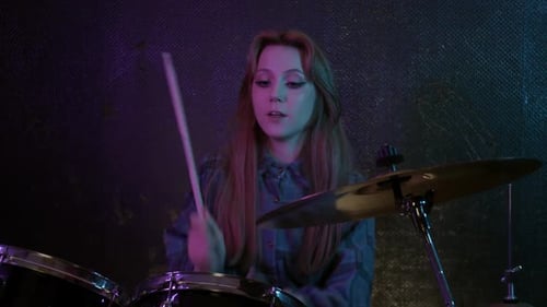 Teen Drummer with Sticks Under Neon Lights