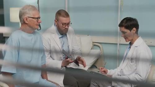 Doctors Discussing Treatment Plan with Senior Patient in Hospital Ward