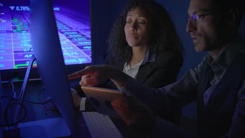 Colleagues Analyzing Stock Data at Night