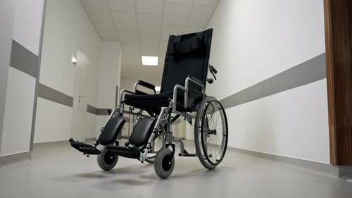 in a Modern Clinic in White Corridor There is a New Black Chair for the Disabled Assistance in