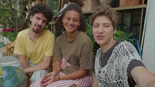 Joyous Friends Chatting on Camera in Outdoor Cafe