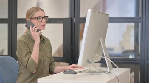 Woman Talking on Phone While Working on Computer