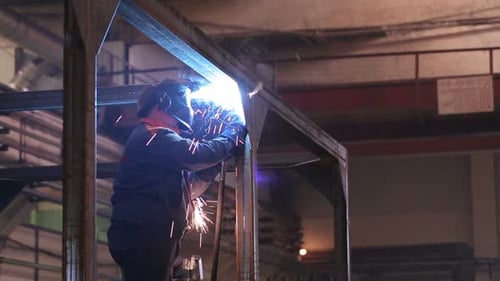 Weld Of Steel Detail Indoors The Plant Close Up. Man Working In Gloves And Protective Wear, Helme...
