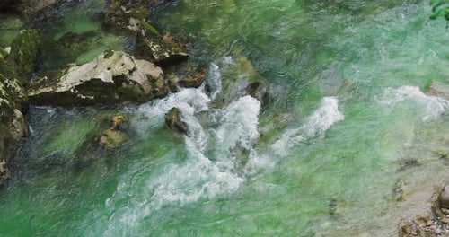 Mountain river with rapids and clear emerald water flow in rocky gorge.