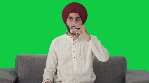Happy Sikh Indian man taking medicine Green screen