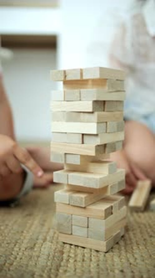 Girl Pulling Out a Brick From a Jenga Tower Closeup