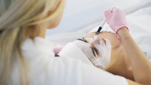 Poner la crema con brocha. Vista de cerca de una mujer que está acostada en el spa