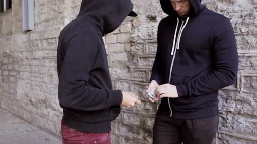 Man exchanging money with person near brick wall