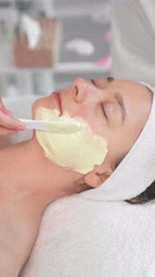 Woman Receiving Cream Facial in Beauty Spa