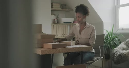 Woman Labels Packages at Home Office Desk