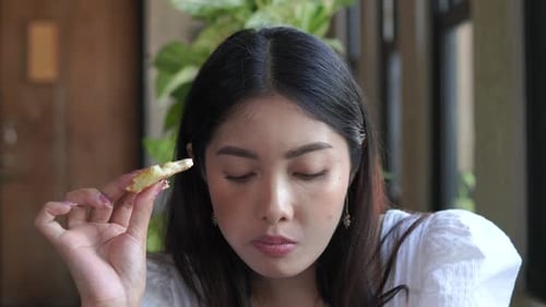 Beautiful woman wearing top white blouse eating pizza at a cafe for lunch.