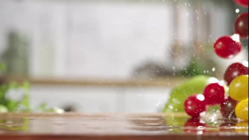 Slow motion of mix of cherry tomatos falling on wet wooden board in a kitchen