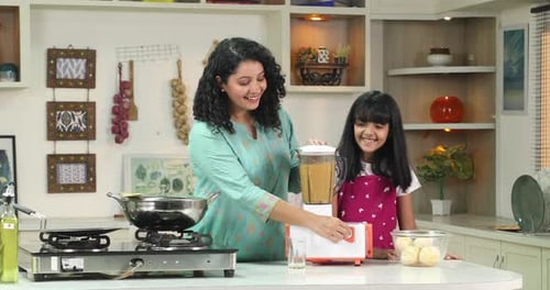 Woman and Girl Blending Food in Kitchen